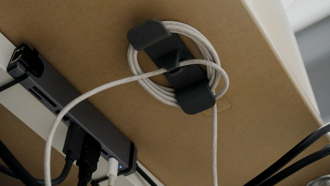 Cable organizer holding coiled white cord under desk